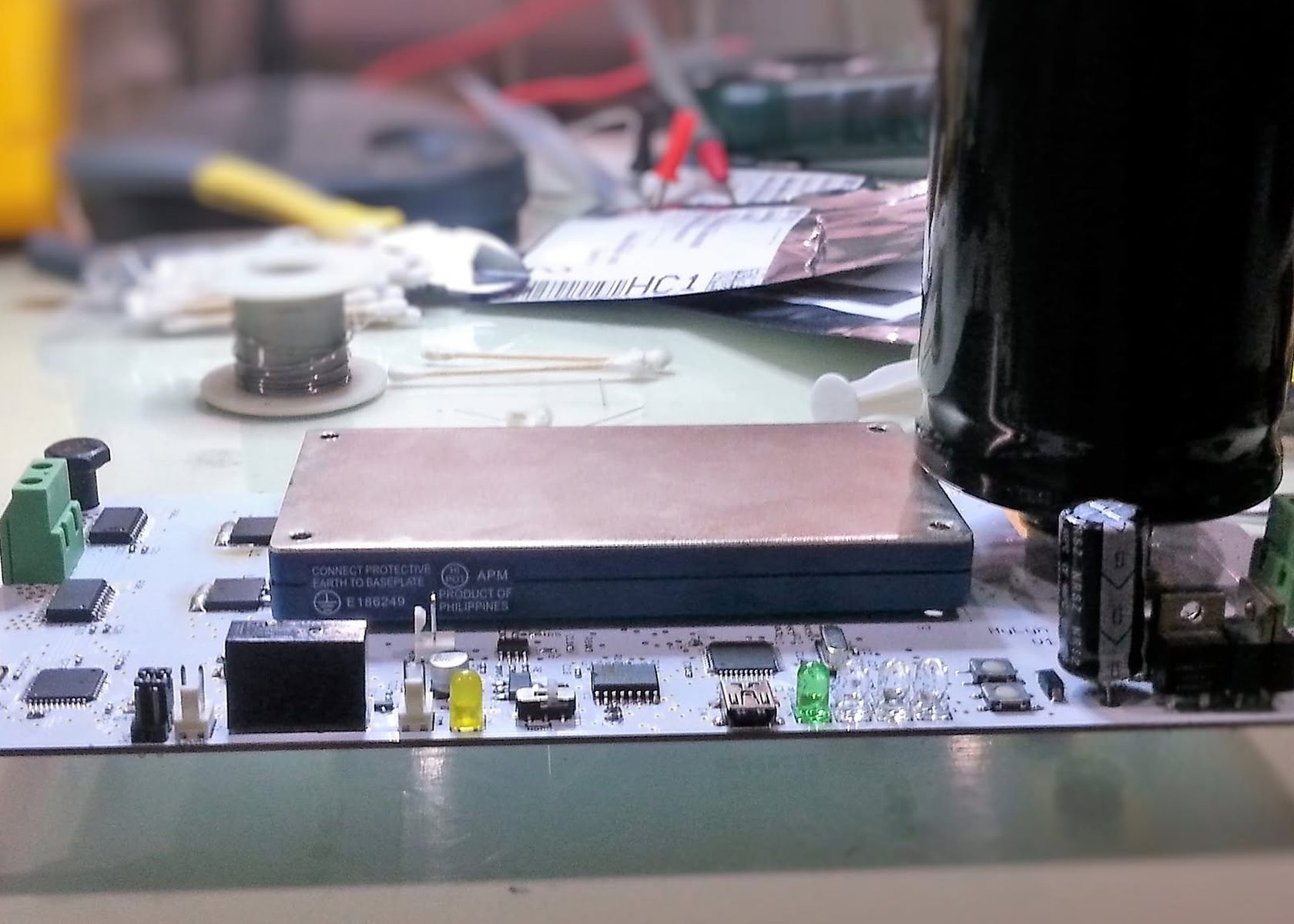 Assembled transformerless power supply board on a workbench, showing the encapsulated converter module, filter capacitor, and terminal blocks